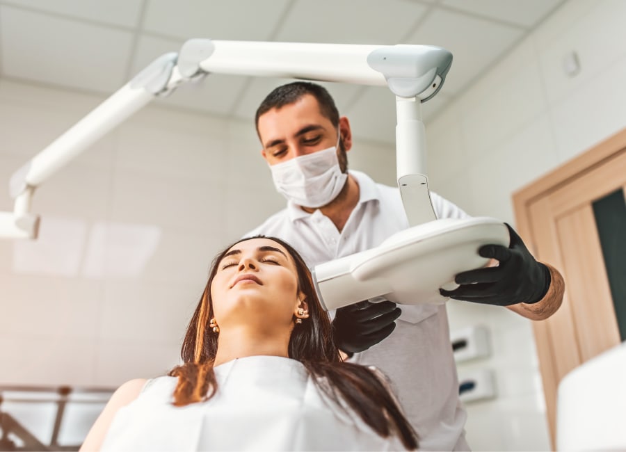 Woman sitting in a dental chair while a dentist takes a dental X-ray.