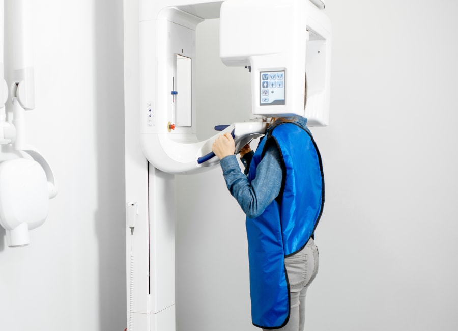 A patient stands with their face in a 3D iCAT Scan machine.
