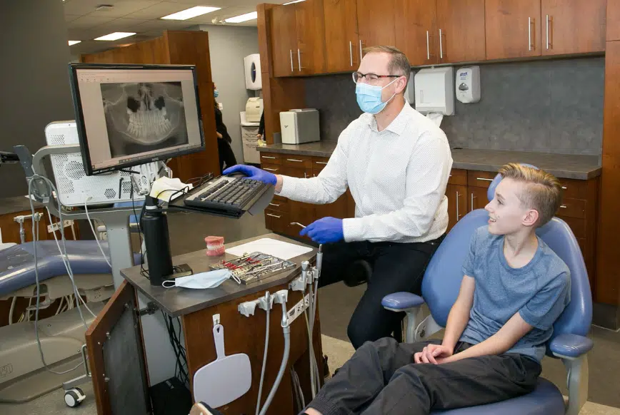 Young woman smiling while receiving a dental X-ray during her appointment.