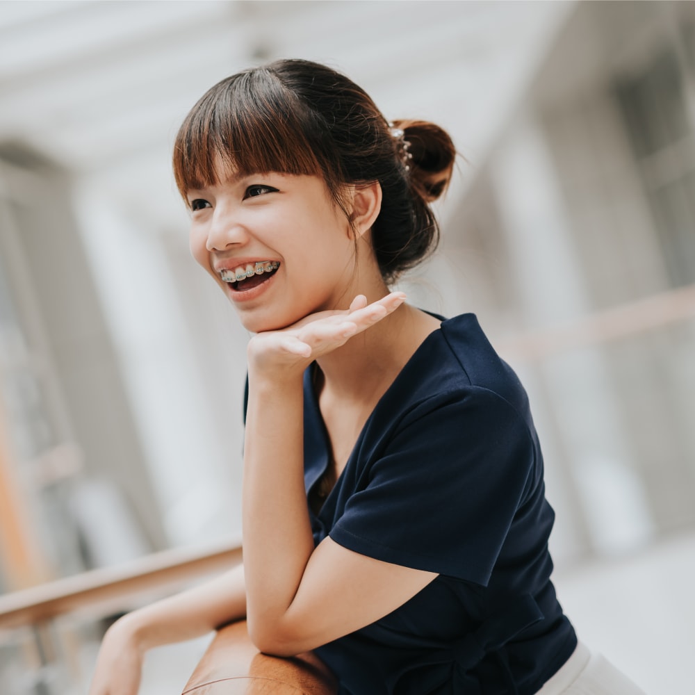 Teenage girl is smiling and showing off braces.