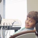 Charming young boy smiling to the camera, sitting in dental chair