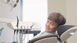 Charming young boy smiling to the camera, sitting in dental chair